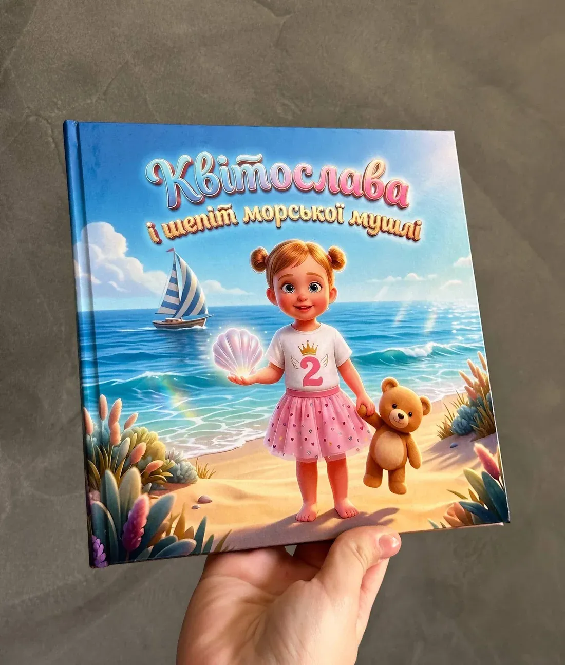 Друкована іменна казка «Квітослава і шепіт морської мушлі» у твердій обкладинці в руці